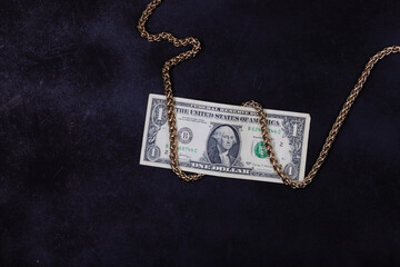 Fototapeta na wymiar dollars and a gold chain on a black and blue background