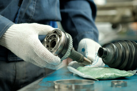 Car maintenance and repair in the car center. A joint of equal angular velocities in the hands of an auto mechanic. Inspection and control of the conformity and integrity of the spare part.