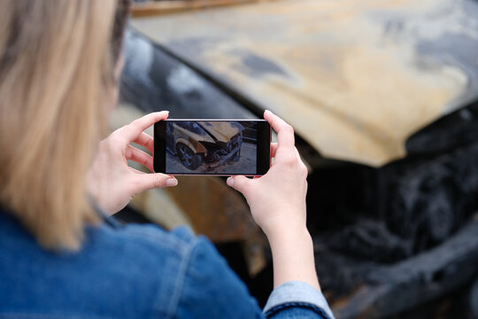 insurance agent or investigator takes picture on smartphone of car after arson