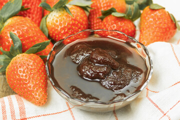 Strawberry jam in a glass bowl and fresh berries on the table