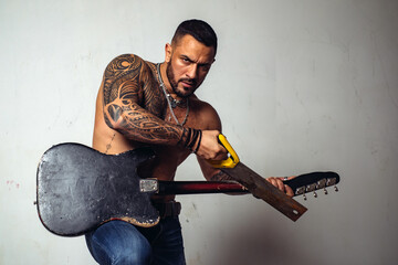 Guitarist breaks guitar. Excited man with electric guitar. Crash electric guitar.