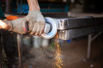 Grinding of metal. Sparks from power tools. The man works in the garage.