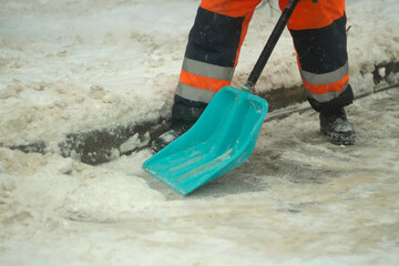 Cleans snow with a shovel. Workers are cleaning the roads after a snowfall.