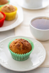 Homemade muffin with colorful paper cups, in a plate served with cup of tea