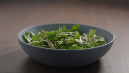 making salad, pour dressing over frisee lettuce in blue bowl on wood table