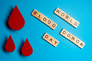 Blood drop symbol on blue background. Text of blood donor day.