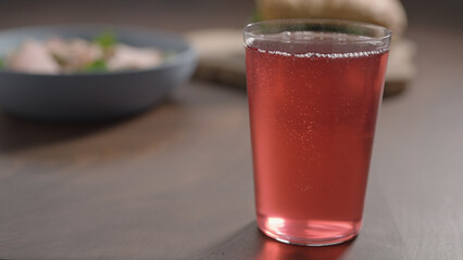 pour pink drink in tumbler glass on wood table
