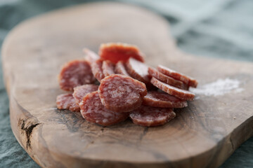 Sliced cured sausage on olive serving board