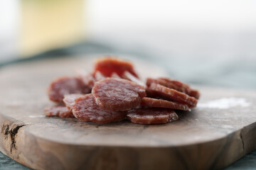 Sliced cured sausage on olive serving board