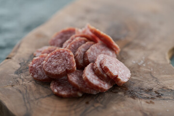 Sliced cured sausage on olive serving board