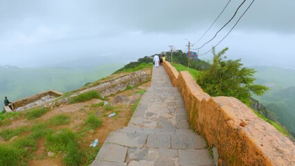 4k video of Beautiful view of stairs of Girnar hills with clouds in sky. At Junagadh, Gujarat, india. Mountain covered with fog and green grass during monsoon season. 