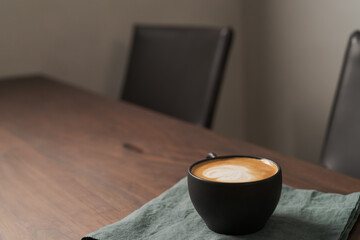 Flat white coffee in black cup on wood table with copy space