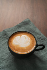 Flat white coffee in black cup on wood table with copy space