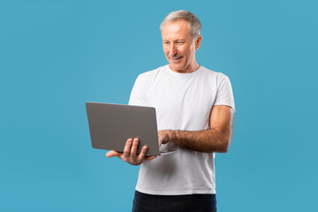 Confident mature man holding and using laptop