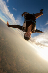 Beautiful woman skydiving in headdown position at sunset, freedom concept