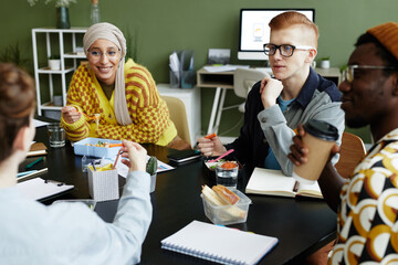 Portrait of creative young man working with diverse design team at business meeting and enjoying...