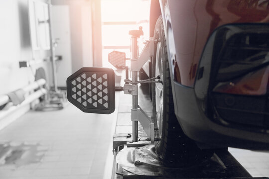 Closeup Car Wheel Alignment On Stand With Sensors Check In Service Station. Vehicle Inside Garage Workshop For Auto Camber Fixing Work