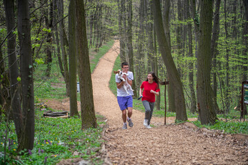 A young girl and a boy run through the woods with their dog