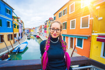 Happy traveler woman having fun near colorful houses on Burano island in Venetian lagoon. Travel...