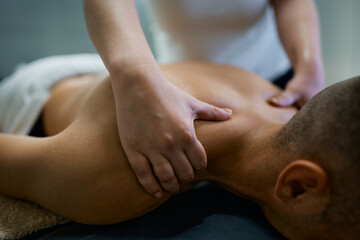 Close up of man receiving shoulder massage at physical therapy center.