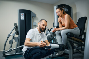 Young sportswoman and her physical therapist going through exercise plans at rehabilitation center.