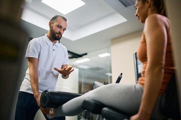 Personal trainer assists sportswoman with her rehabilitation treatment at health club. - Powered by Adobe