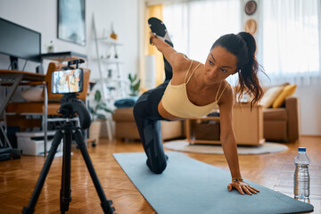 Fototapeta na wymiar Fitness instructor doing stretching exercises while recording video for her vlog t home.
