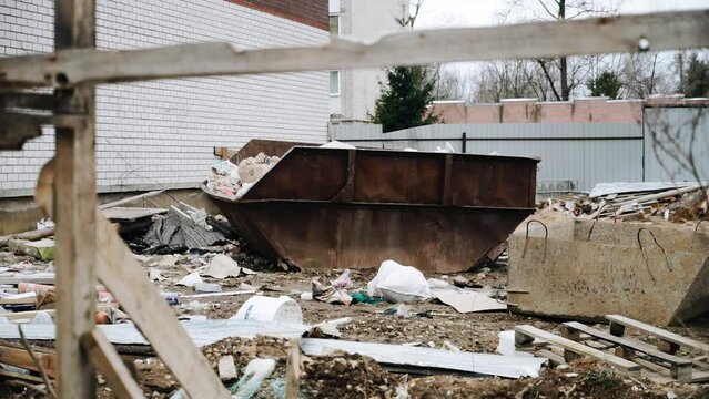 Next to the house under construction there is a container with garbage and trash lying around. Mess at the construction site
