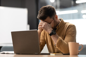 Desperate Businessman Near Laptop Covering Face Having Problem In Office