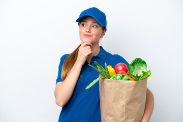 Young delivery woman taking a bag of takeaway food isolated on white background looking up while smiling