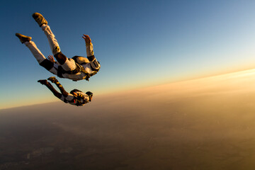 Fototapeta Skydiving couple in freefall at sunset, togetherness concept obraz