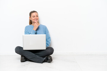 Young woman with a laptop sitting on the floor looking to the side