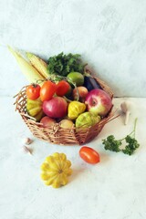 Vegetables, fruits and greens in a wicker basket, on a wooden table, harvest season, organic natural food, healthy food, home cooking
