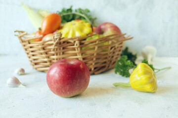 Vegetables, fruits and greens in a wicker basket, on a wooden table, harvest season, organic natural food, healthy food, home cooking