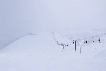 Fototapeta na wymiar Looking down at slope in a ski resort on snowy day (Niseko Hanazono Resort, Hokkaido, Japan)