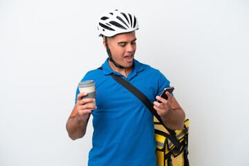 Young caucasian man with thermal backpack isolated on white background holding coffee to take away and a mobile