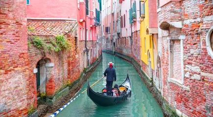 Printed kitchen splashbacks Gondolas Venetian gondolier punting gondola through green canal waters of Venice Italy