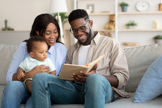 Portrait of happy black family reading book for son