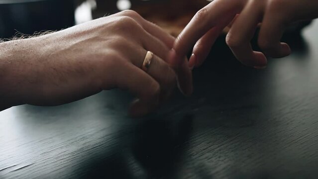 Lovers are sitting at a table and touching each other's hands. Close-up shooting of hands