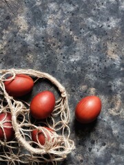 Painted Easter eggs in string bag on black concrete background with copy space. Easter concept. Easter greeting card.