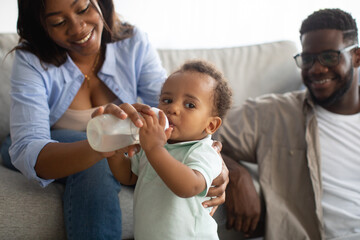 Young African American parents feeding child from bottle