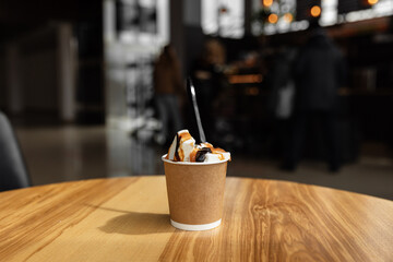 Ice cream with coffee in a disposable cup to take away. Isolated paper cup with ice cream on the table in a cafe