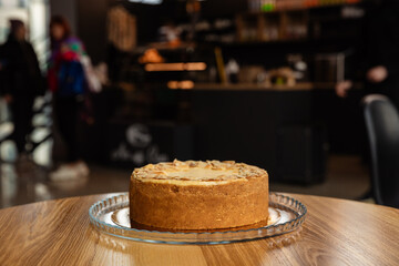 Fresh delicious cake sprinkled with almonds. Baking in a coffee shop. Isolated cake on a dark background with day light.