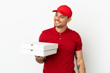 pizza delivery man with work uniform picking up pizza boxes over isolated  white wall looking to the side and smiling