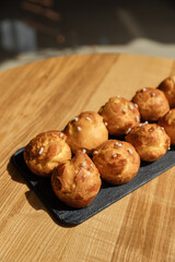 Ball cakes with custard on a wooden table. Delicious pastries for coffee in a cafe under the sun isolated