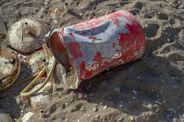 Rusty barrel thrown on the beach, hose, garbage, environmental pollution