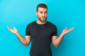 Young handsome caucasian man isolated on blue background having doubts while raising hands