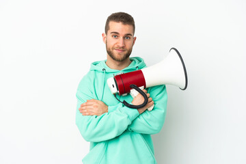 Young handsome caucasian man isolated on white background holding a megaphone and smiling