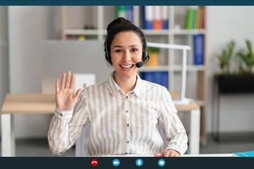 Head shot of cheerful female employee worker waving hand to webcam, greeting colleagues at online...