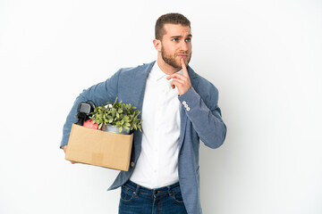 Young caucasian making a move while picking up a box full of things isolated on white background...